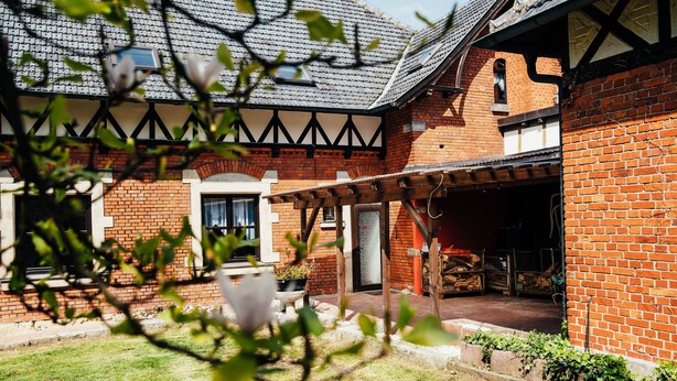 A brick house with a covered porch and a garden. - Apartment in historical building - old school (Spittelstein)