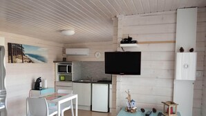 Un espace de vie compact comprenant un coin cuisine, un coin repas et un téléviseur fixé au mur.
