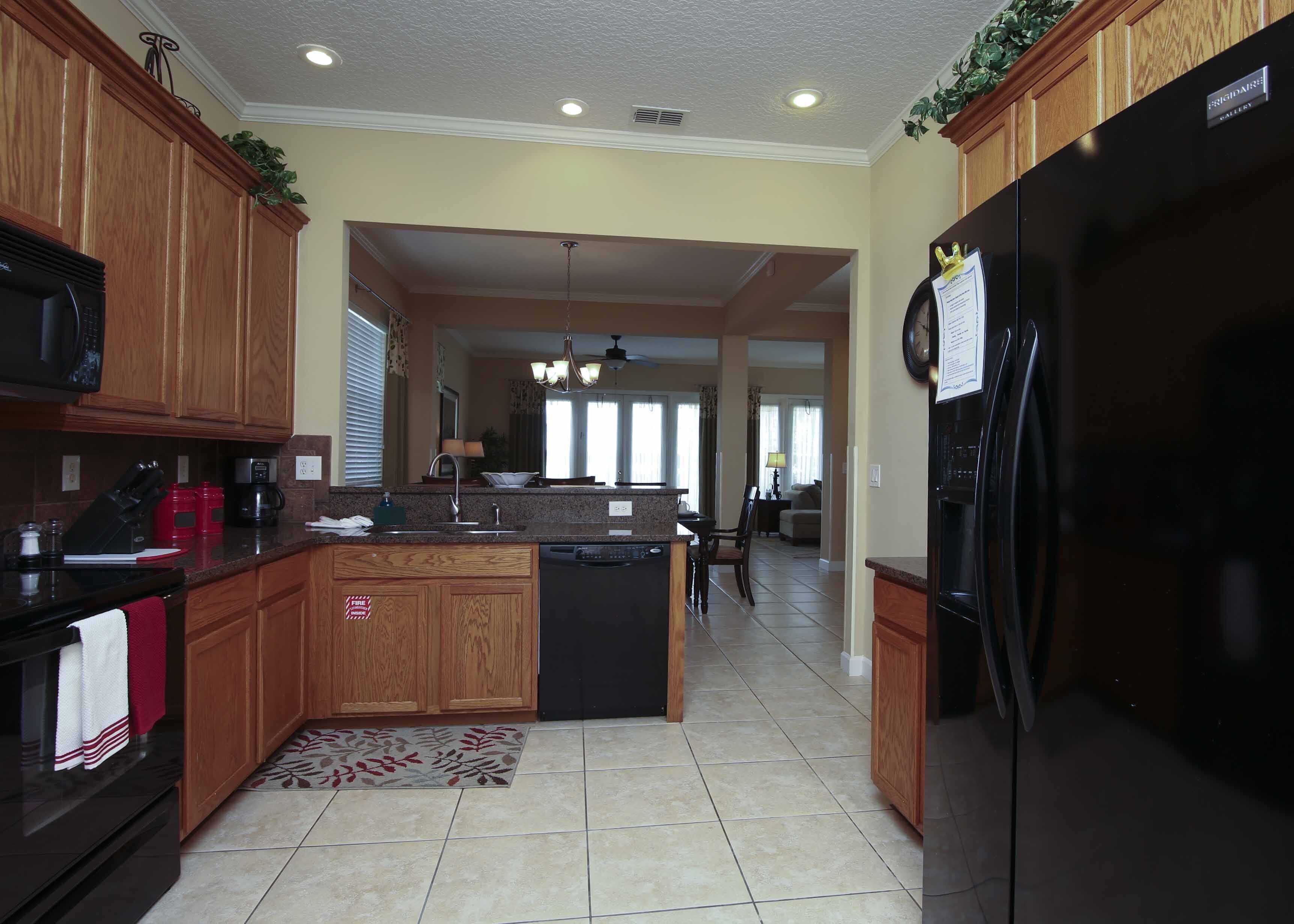 A modern kitchen with wooden cabinets, a black refrigerator, and a central island.