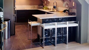 Een moderne keuken met een centraal eiland, barkrukken en een roestvrijstalen koelkast.