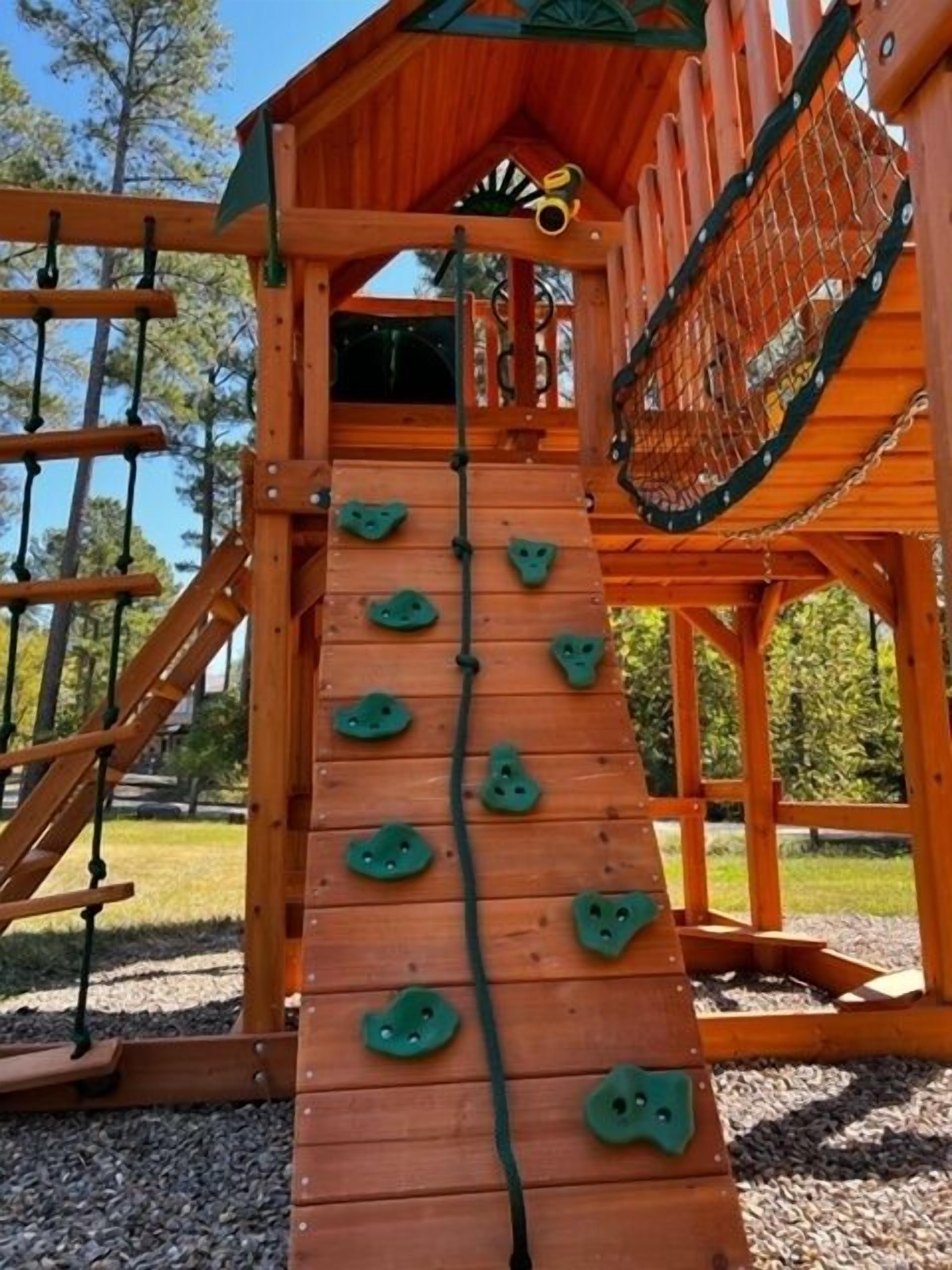 Una estructura de madera para escalar con una escalera de cuerda y barras colgantes.
