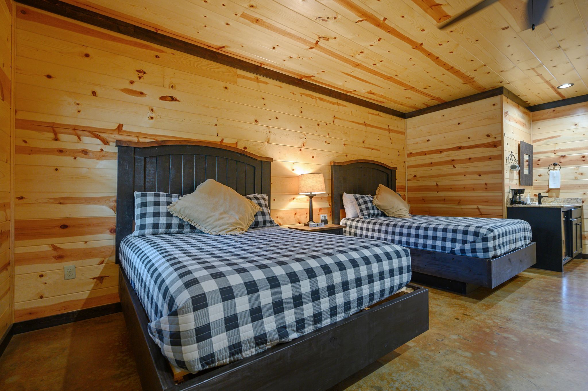 A wooden cabin with two beds, each with a checkered bedspread and pillows.