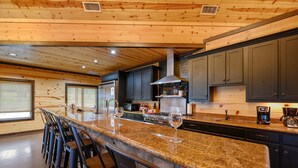 A kitchen with granite countertops, dark cabinets, and a central island with bar stools.