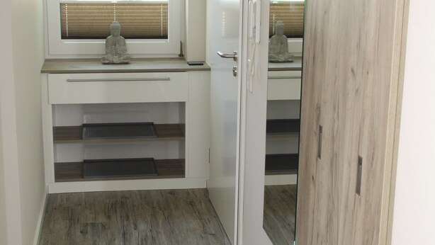 Ein Zimmer mit Schreibtisch, Fenster mit Jalousien, Spiegel und Kleiderschrank.