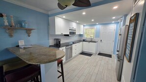 Une cuisine moderne avec des armoires blanches, un comptoir en granit et un ventilateur de plafond.