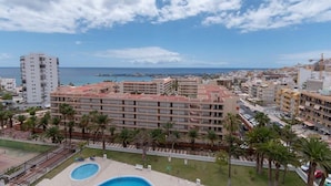 Ett hotell med pool, palmer och utsikt över havet.