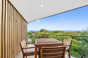 A wooden deck with a table and chairs, overlooking a coastal landscape. - Point Break (Anglesea)