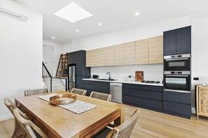 Eine moderne Küche mit dunklen Schränken, einem Holztisch und einem eingebauten Backofen.
