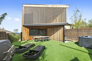 A modern two-story building with a flat roof, a wooden facade, and a large window.