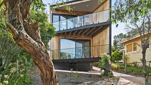 A modern two-story house with a balcony, large windows, and a wooden exterior. - Point Break (Anglesea)