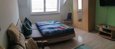 A bedroom with a bed, a sofa, a TV, and a wardrobe.