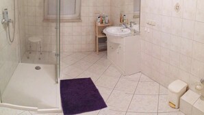Un baño con ducha acristalada, lavabo e inodoro.
