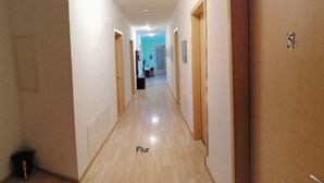 Un pasillo con suelo de madera y puertas a ambos lados.