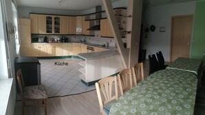 Una cocina compacta con armarios de madera y un comedor con mantel floreado verde.