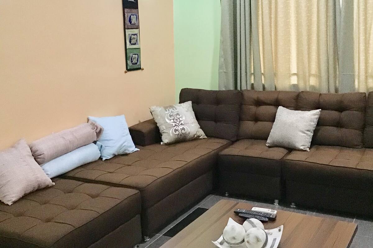 A living room with a sectional sofa, a coffee table, and a wall-mounted light fixture.