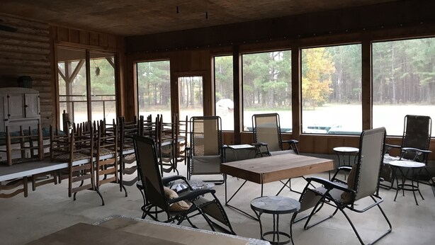 A rustic cabin with wooden walls and large windows offering a view of a forest. - Cabin in the woods between Mt. Nebo and Mt. Magazine (Dardanelle)