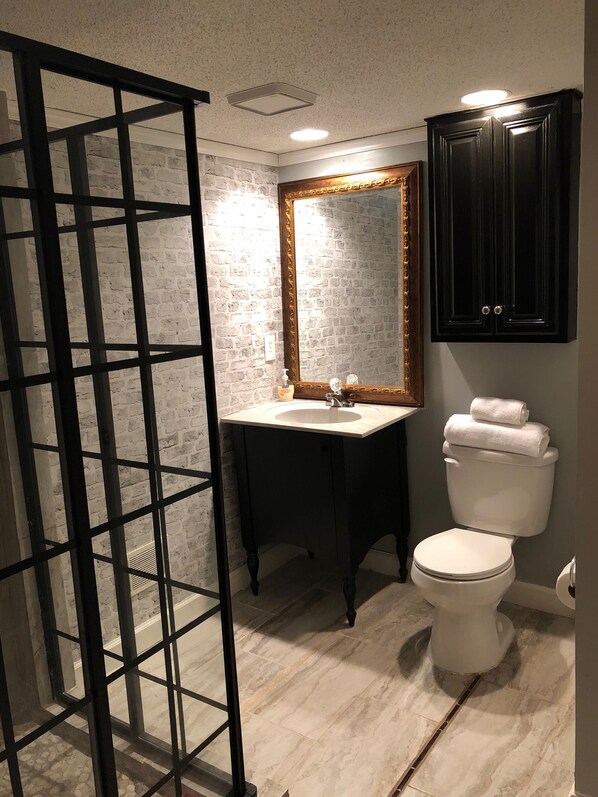 A bathroom with a white sink, a mirror, a toilet, and a black cabinet.