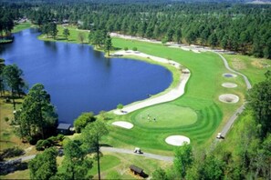 A golf course with a lake, sand bunkers, and a clubhouse. - Amazing Oceanfront 2 Bed 2 Bath Condo in Myrtle Beach (Myrtle Beach)