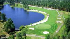 A golf course with a lake, sand bunkers, and a clubhouse.