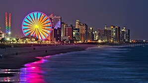 A beachside cityscape with a prominent Ferris wheel and high-rise buildings.