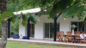 Ein modernes Haus mit Terrasse, einem Esstisch mit Stühlen und einem blauen Sofa.