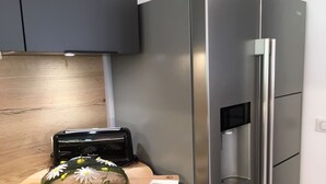 Eine moderne Küche mit einem Edelstahlkühlschrank, einem Toaster und einer dekorativen Glasplatte mit Blumen auf einer Holz Arbeitsfläche.