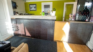 A compact kitchen with a countertop, a refrigerator, and a door leading to another room. - Camrose Motel (Camrose)