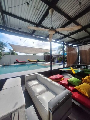 An outdoor pool area with lounge chairs and a covered seating area. - Labrish Guest House (Kingston)
