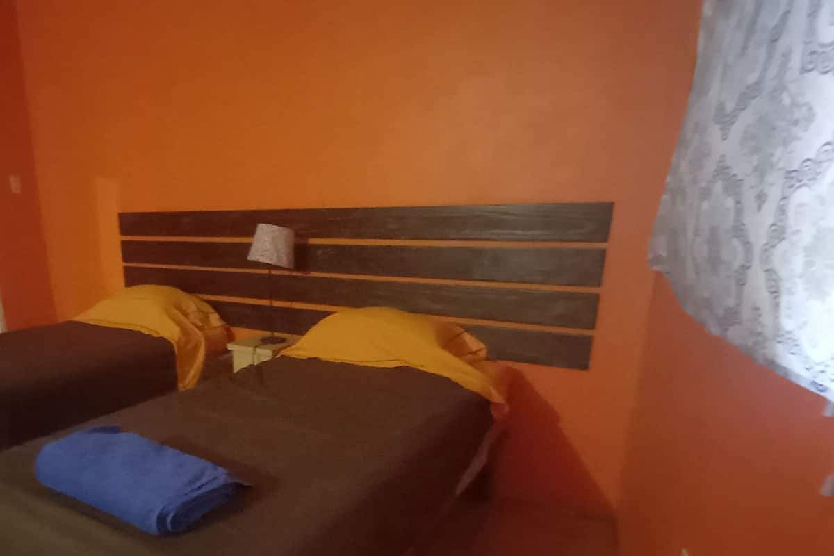 A room with two beds, a door, and a patterned curtain.