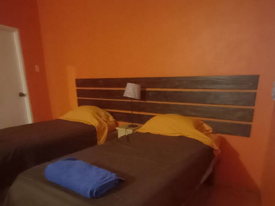 Une chambre avec deux lits, une porte et un rideau à motifs.