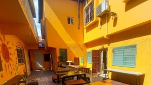 A courtyard with yellow walls, geometric patterned floor, and outdoor seating with benches and tables. - Labrish Guest House (Kingston)
