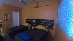 A room with two beds, a ceiling fan, a door, and a patterned wall. - Labrish Guest House (Kingston)