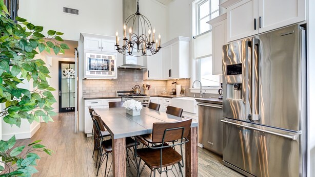A modern kitchen with a central island, stainless steel appliances, and a chandelier.