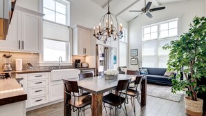 A spacious kitchen with white cabinetry, a dining table, and a chandelier.
