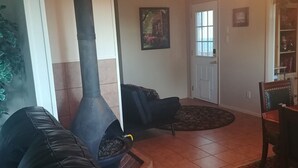 Un soggiorno con stufa a legna, divano in pelle nera, tavolo da pranzo e tappeto decorato.