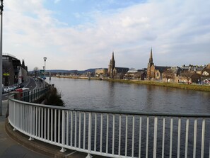 A riverside view with a bridge, buildings, and a white railing. - STAG city centre studio apartment (Inverness)