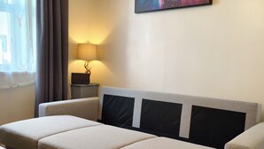 Un salon moderne avec un canapé, une petite table, une lampe et un tableau accroché au mur.
