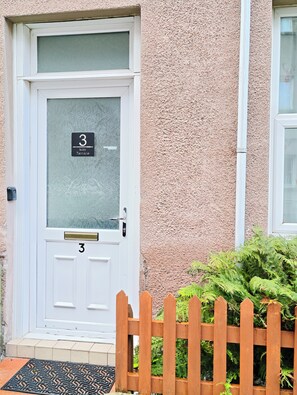 A white door with a number plate reading '3 May Terrace.'