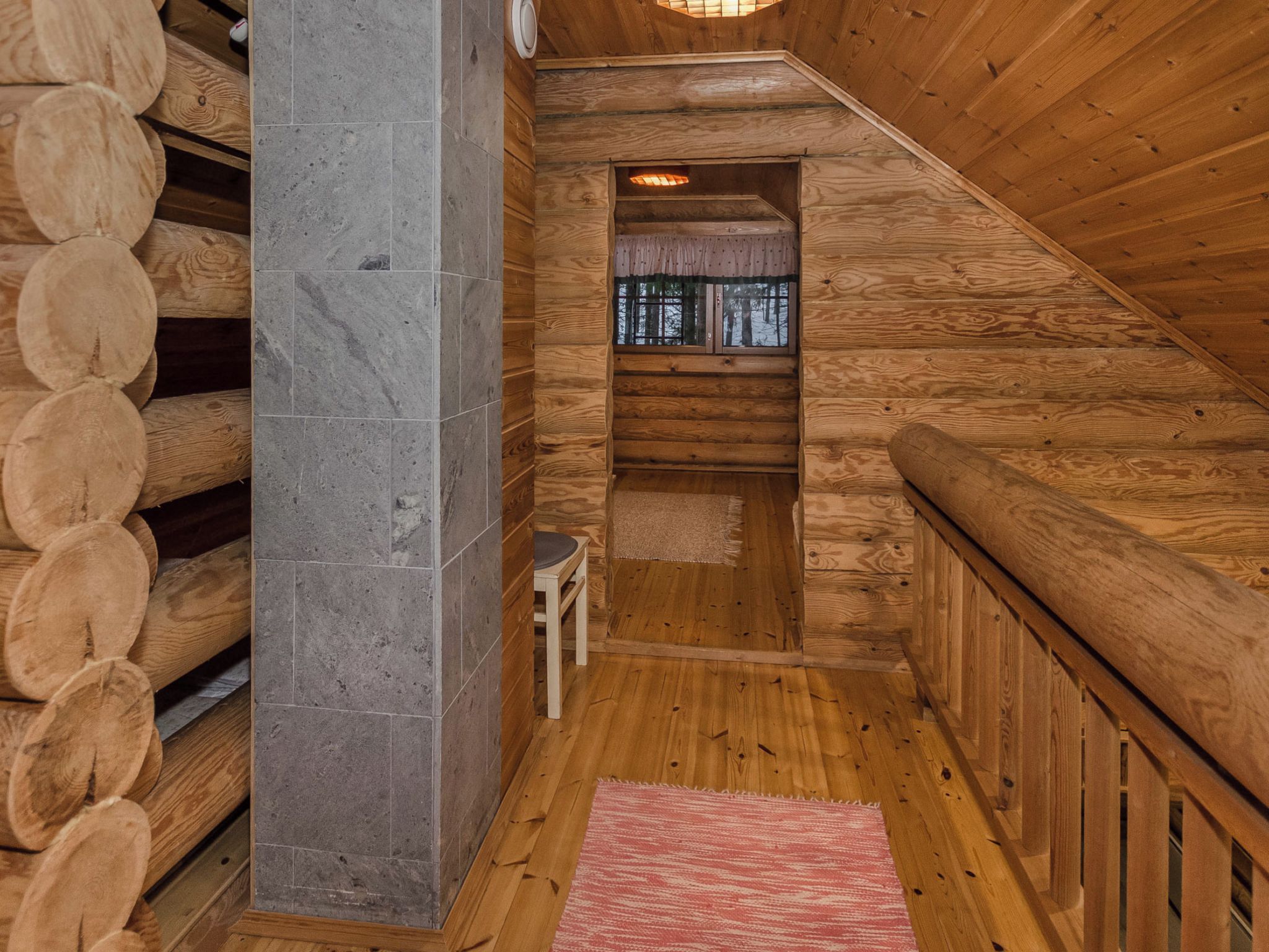 Un interno in legno con un pilastro in pietra, un tavolino e una finestra vista.