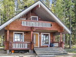 A log cabin with a balcony, a front porch, and a chimney.