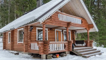 A log cabin with a porch and a chimney.
