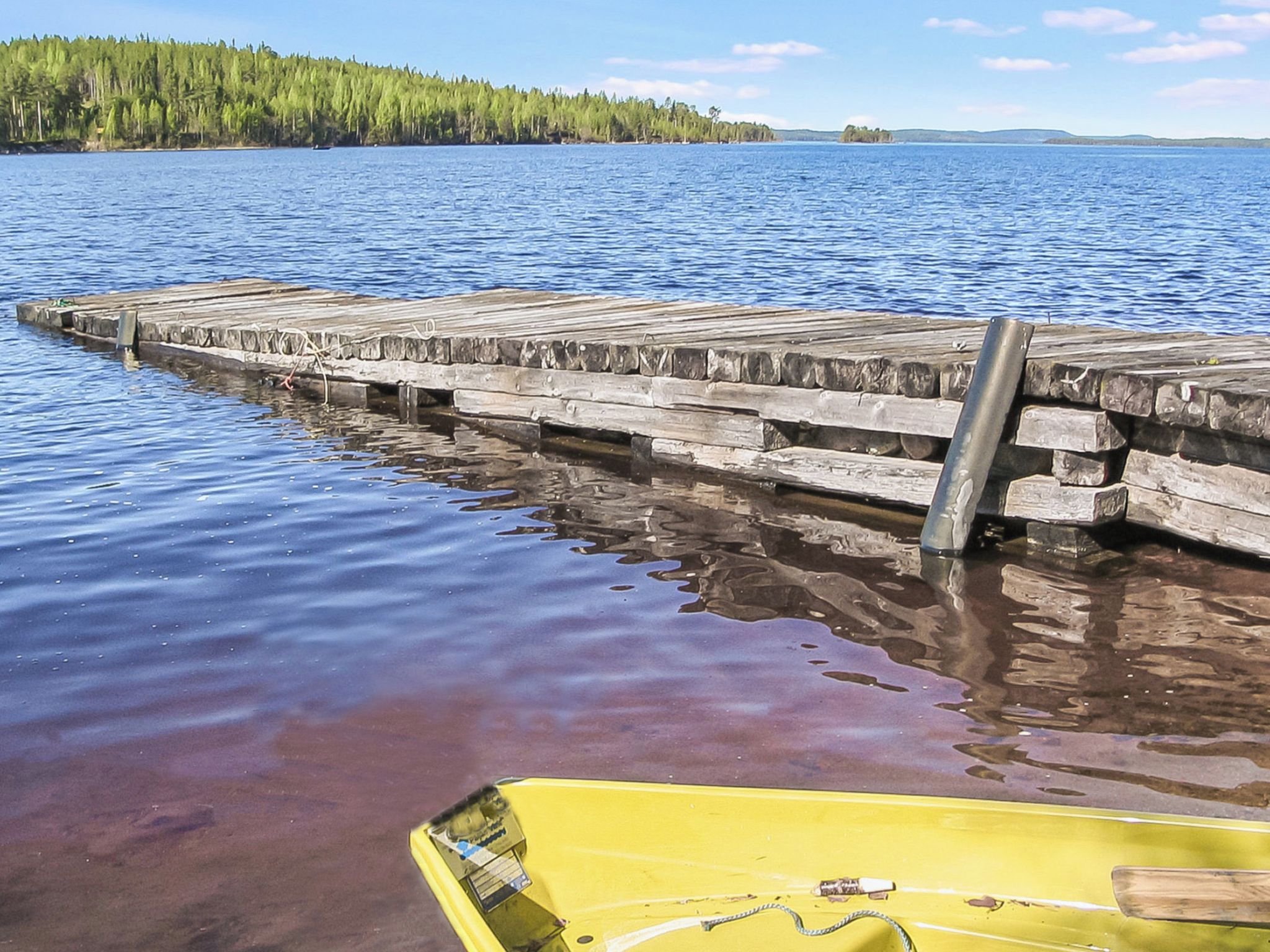A wooden dock extending into a body of water with a yellow boat docked at the end.
