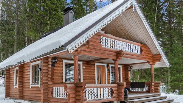 A log cabin with a porch and steps leading up to the entrance.
