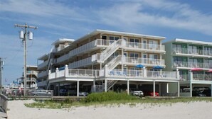 A multi-story beachfront hotel with balconies, a parking area, and a boardwalk. - Beach Block Wildwood Crest Condo (Wildwood Crest)