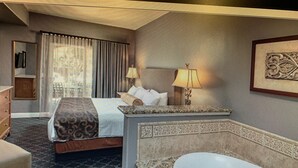 Ein Hotelzimmer mit einem Bett, einem Schreibtisch, einer Lampe, einem Gemälde und einer Badewanne.