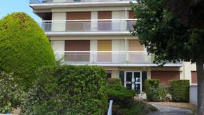 Ein mehrstöckiges Wohngebäude mit Balkonen, einem gepflegten Garten und einem deutlichen Zugang zur Eingangstür.
