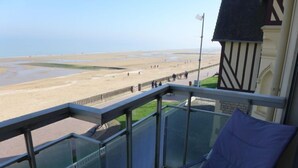 Ein Balkon mit freiem Blick auf einen Strand und ein Gebäude im traditionellen Stil.