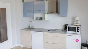 Eine kompakte Küche mit Geschirrspüler, Mikrowelle, Kaffeemaschine und kleinem Kühlschrank.