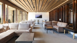 A modern lounge area with sofas and tables, large windows, and a wooden ceiling. - Jeanne D'Arc Apt. E-38 by Interhome (Crans-Montana)