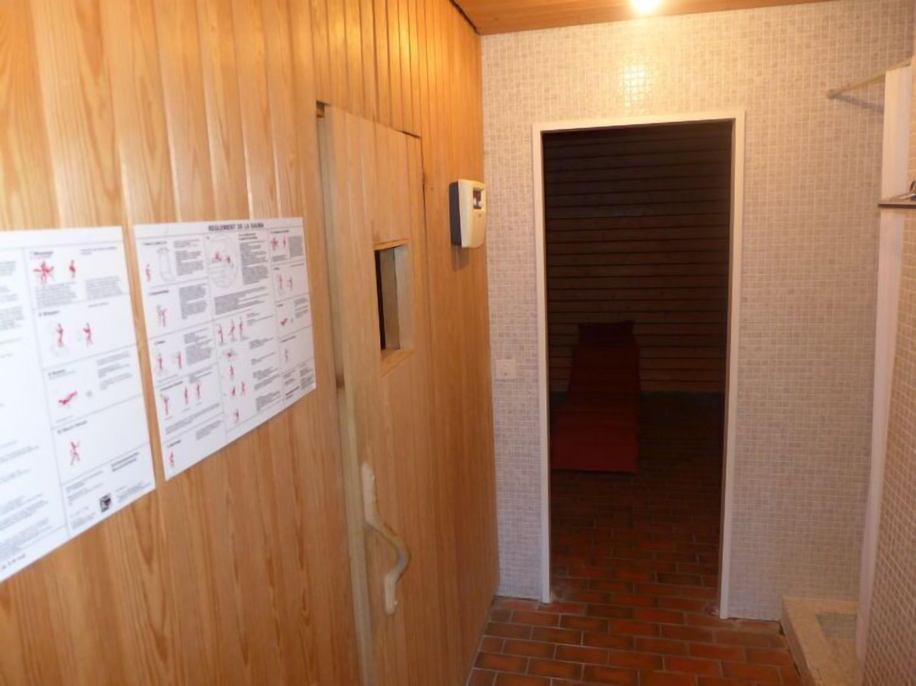 Un pasillo estrecho con paredes de madera y suelo de baldosas, que conduce a una habitación con una puerta roja.